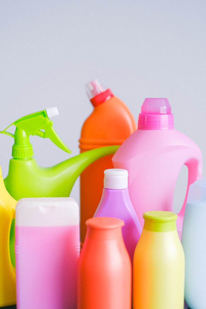 Composition of colorful plastic bottles of cleaners with dispenser for everyday routine placed on table against white background in light room